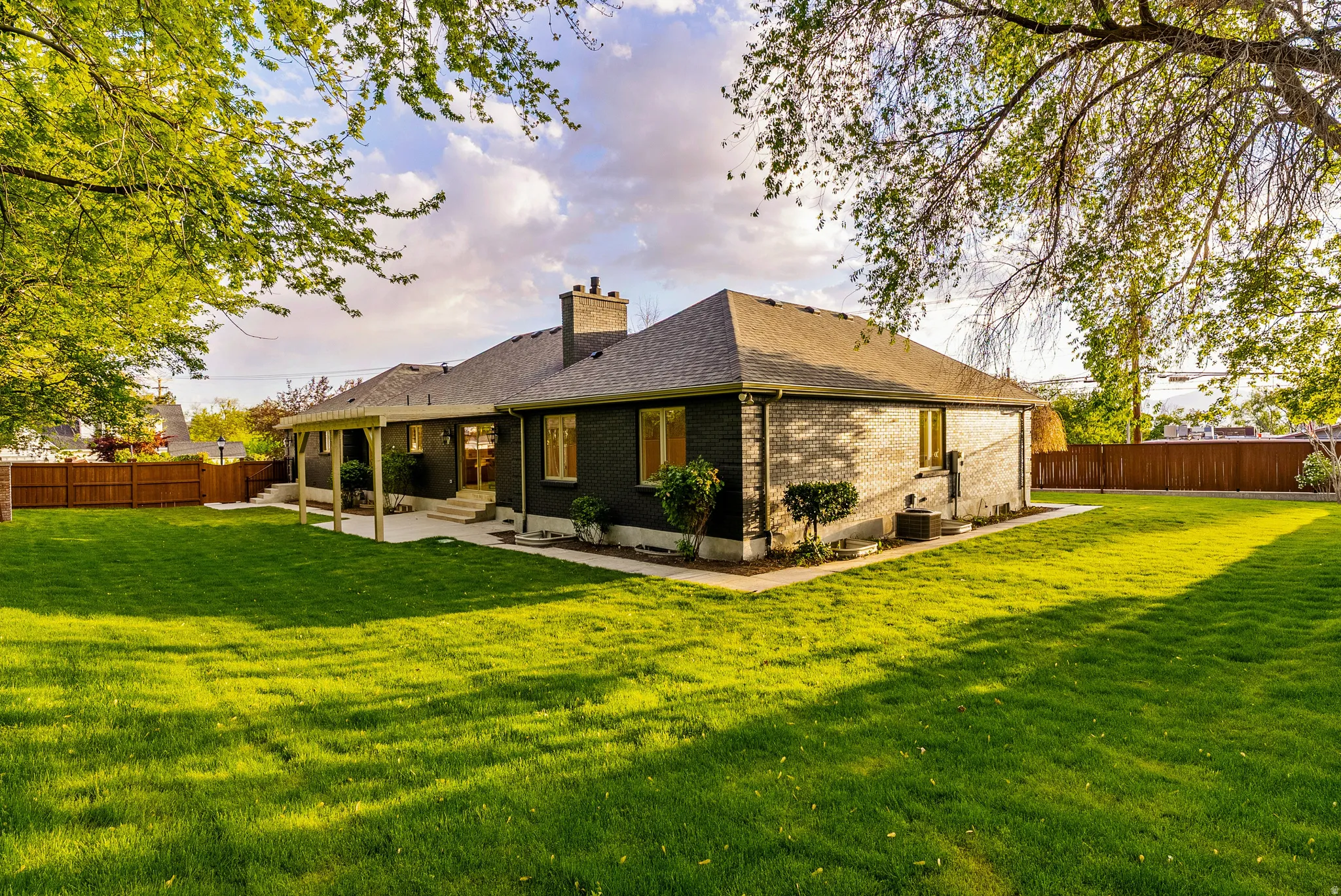 Expansive backyard featuring a manicured lawn, established trees, and a wooden privacy fence