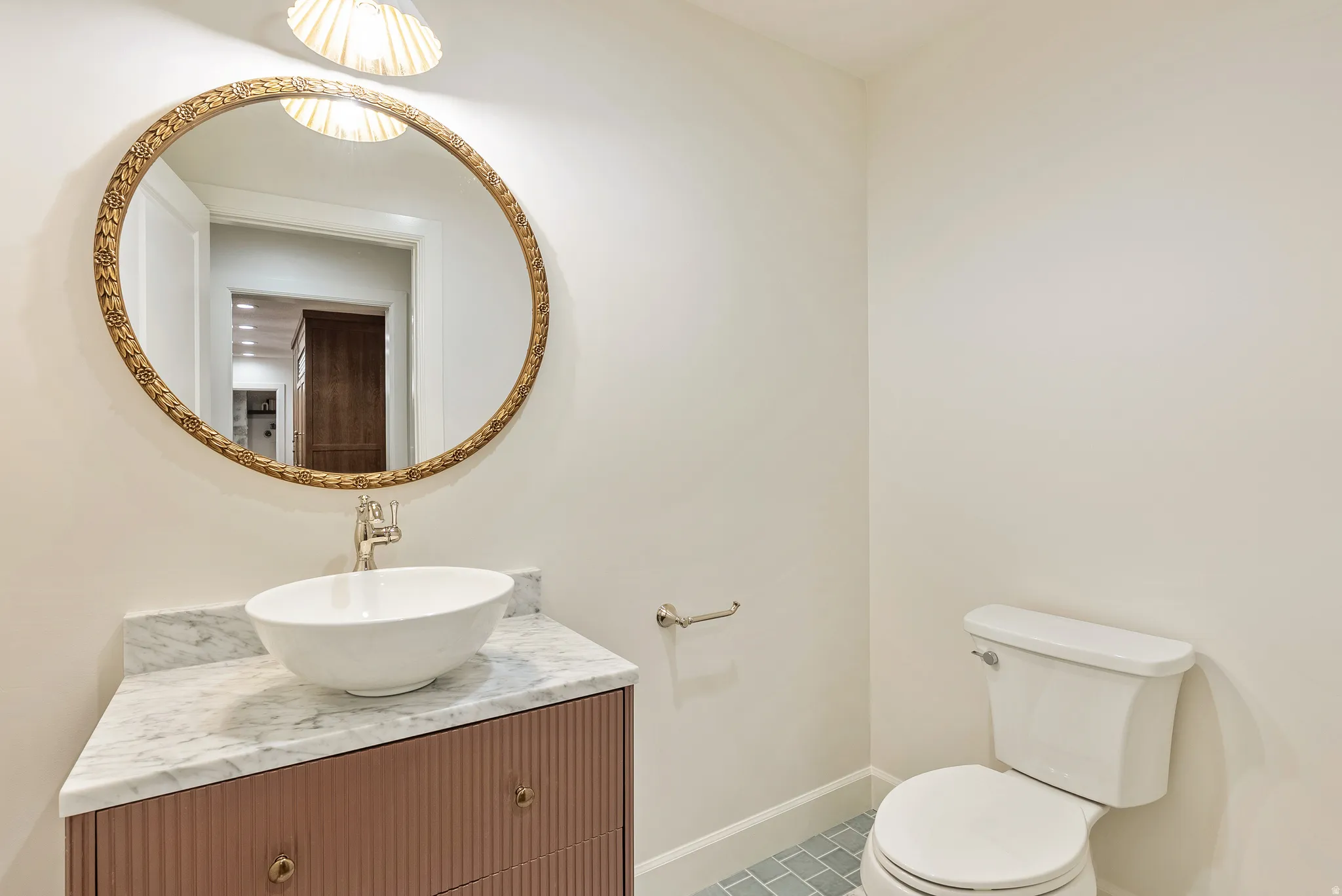 Powder room featuring a vessel sink, marble countertop, and custom vanity with fluted detailing