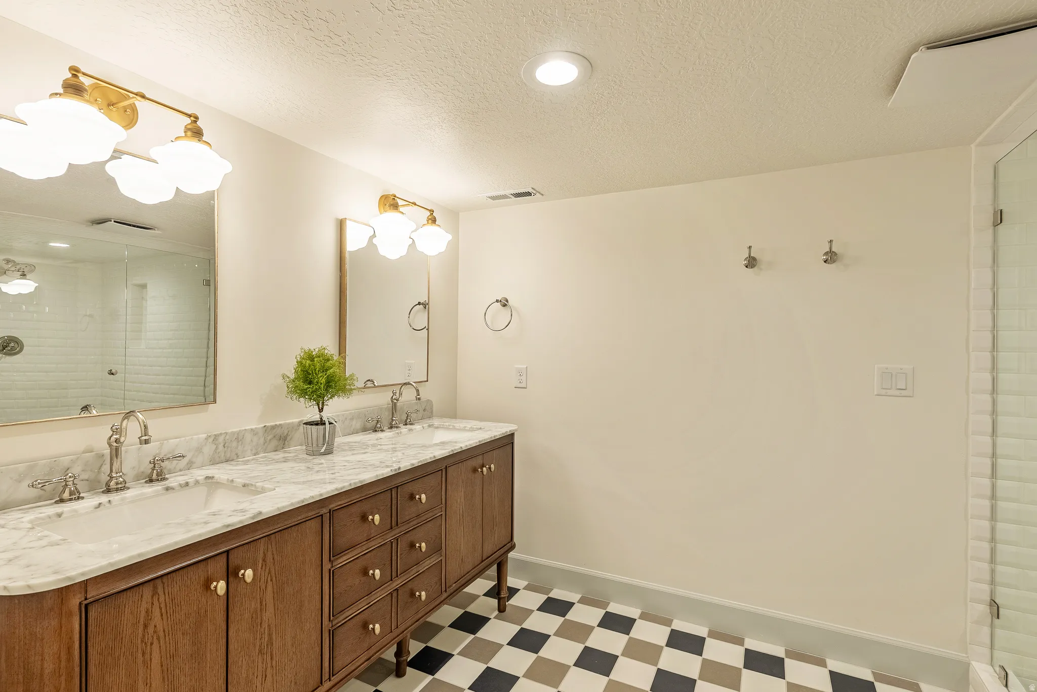 Bathroom featuring a dual vanity with a marble countertop, undermount sinks, and brushed nickel faucets