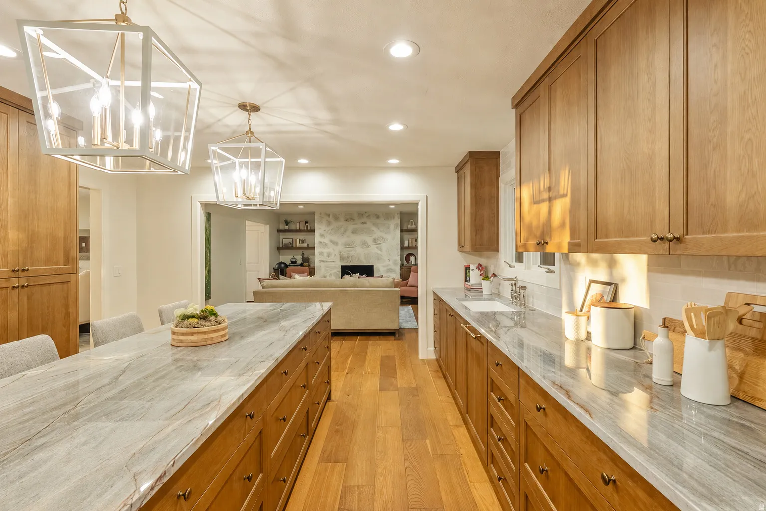 Gourmet kitchen featuring a large central island with seating, ample wood cabinetry, light-toned countertops, and wood-finish flooring