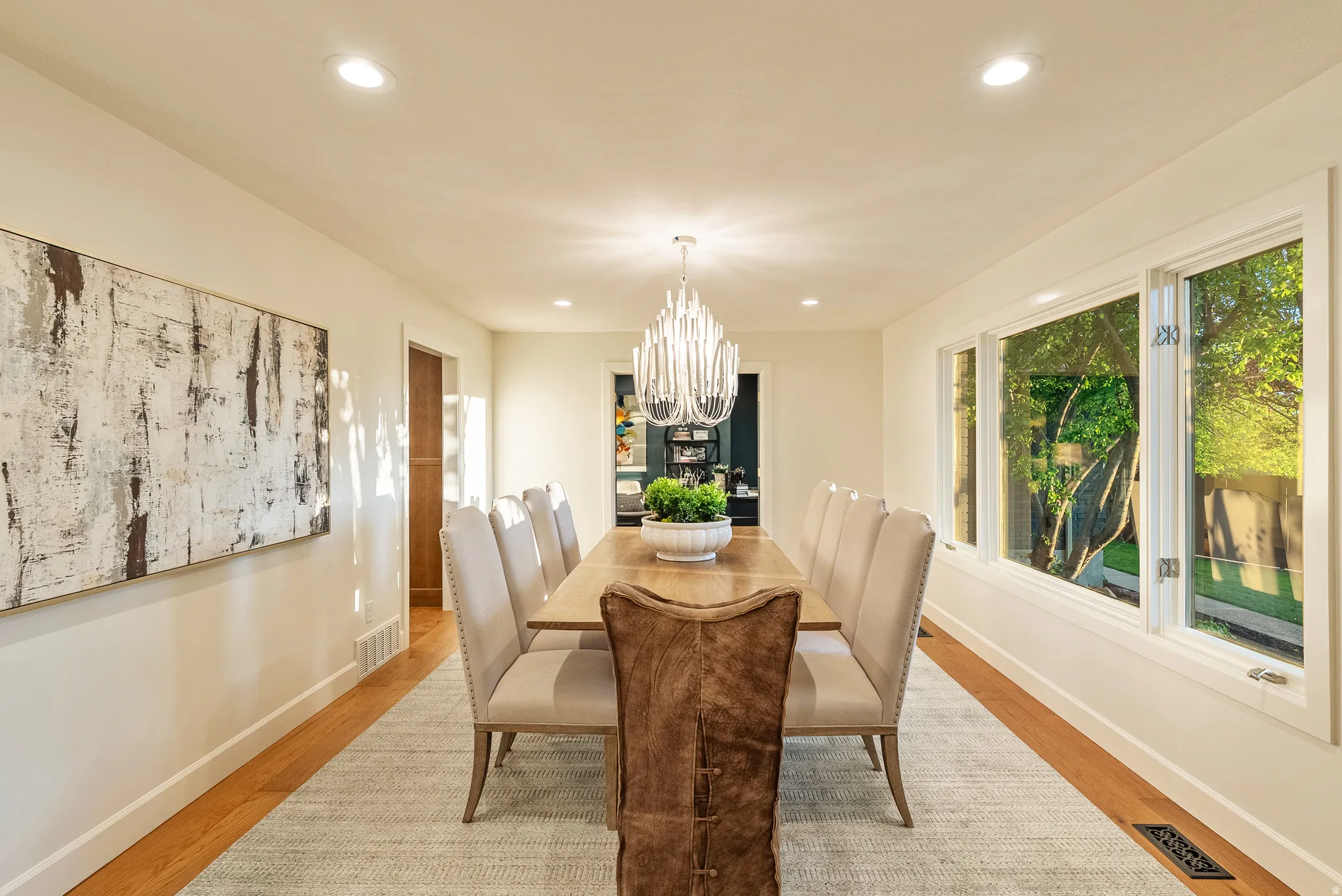 Spacious dining area featuring hardwood flooring, recessed lighting, and a contemporary chandelier