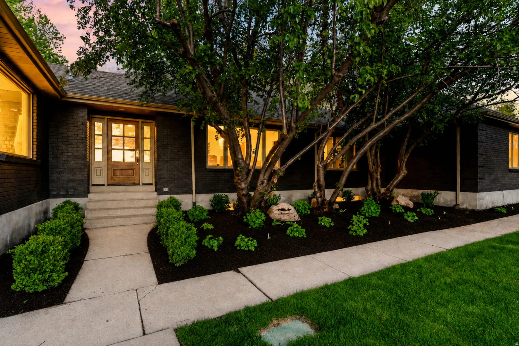Dark-toned brick exterior with a prominent wood-paneled entry door featuring sidelights and a transom