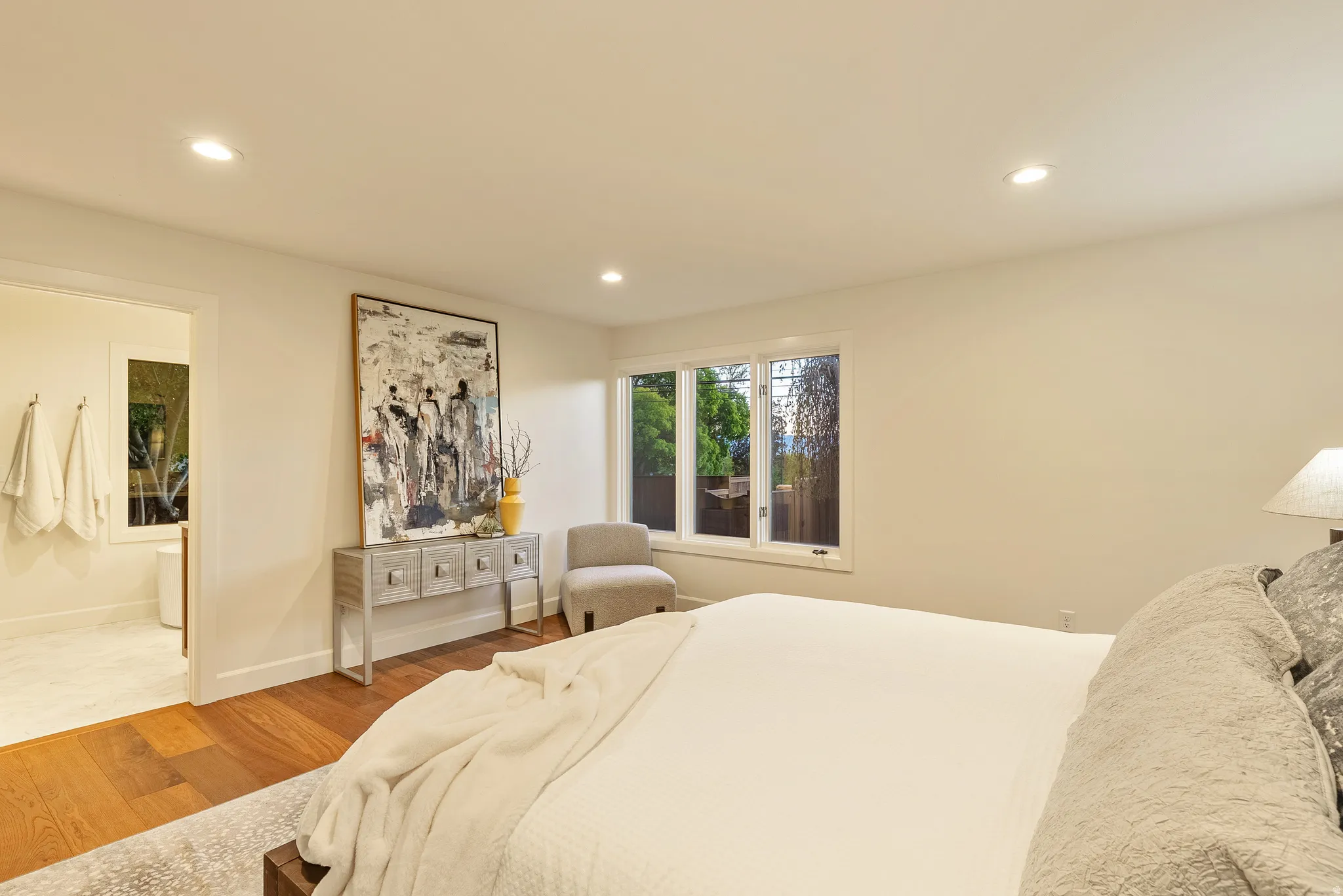 Spacious room featuring rich wood-finish flooring, recessed lighting, and a large window offering natural light