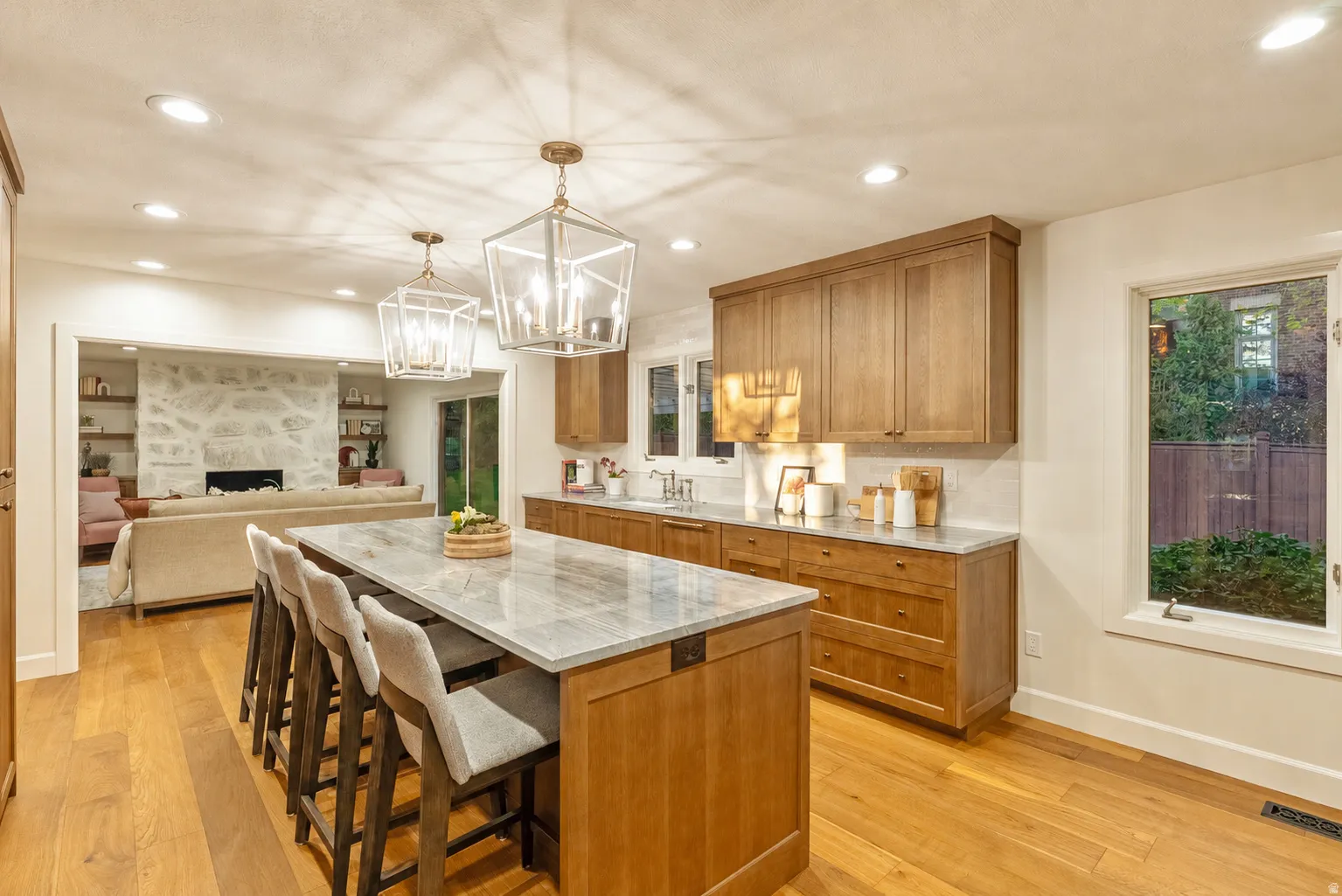 Kitchen featuring wood-finish flooring, a central island with a stone countertop, recessed lighting, and two geometric pendant lights