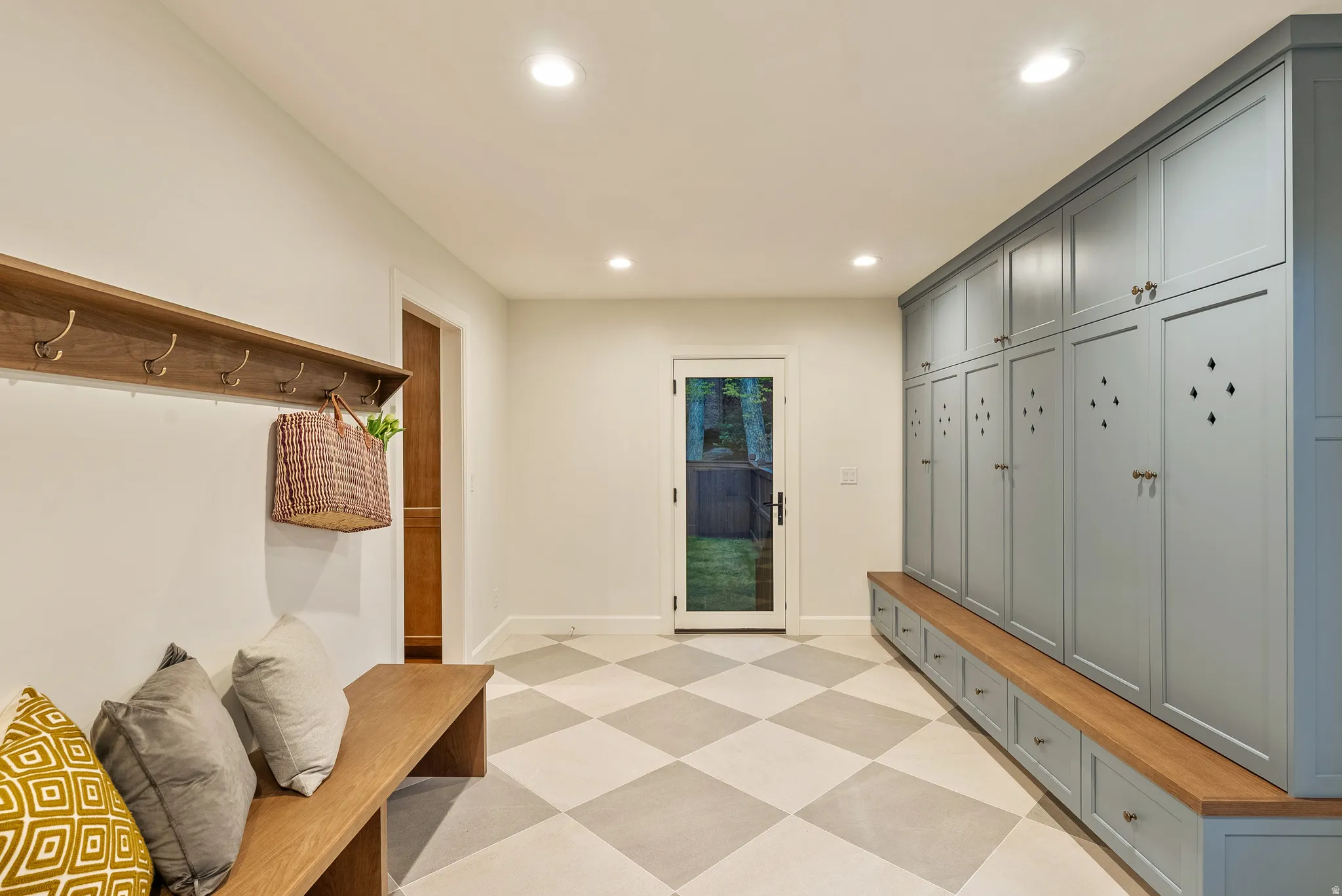 Mudroom featuring extensive built-in cabinetry with a light blue finish, integrated wood-finish bench seating, diamond-patterned floor tiling, a wood-finish coat rack, and recessed ceiling lighting