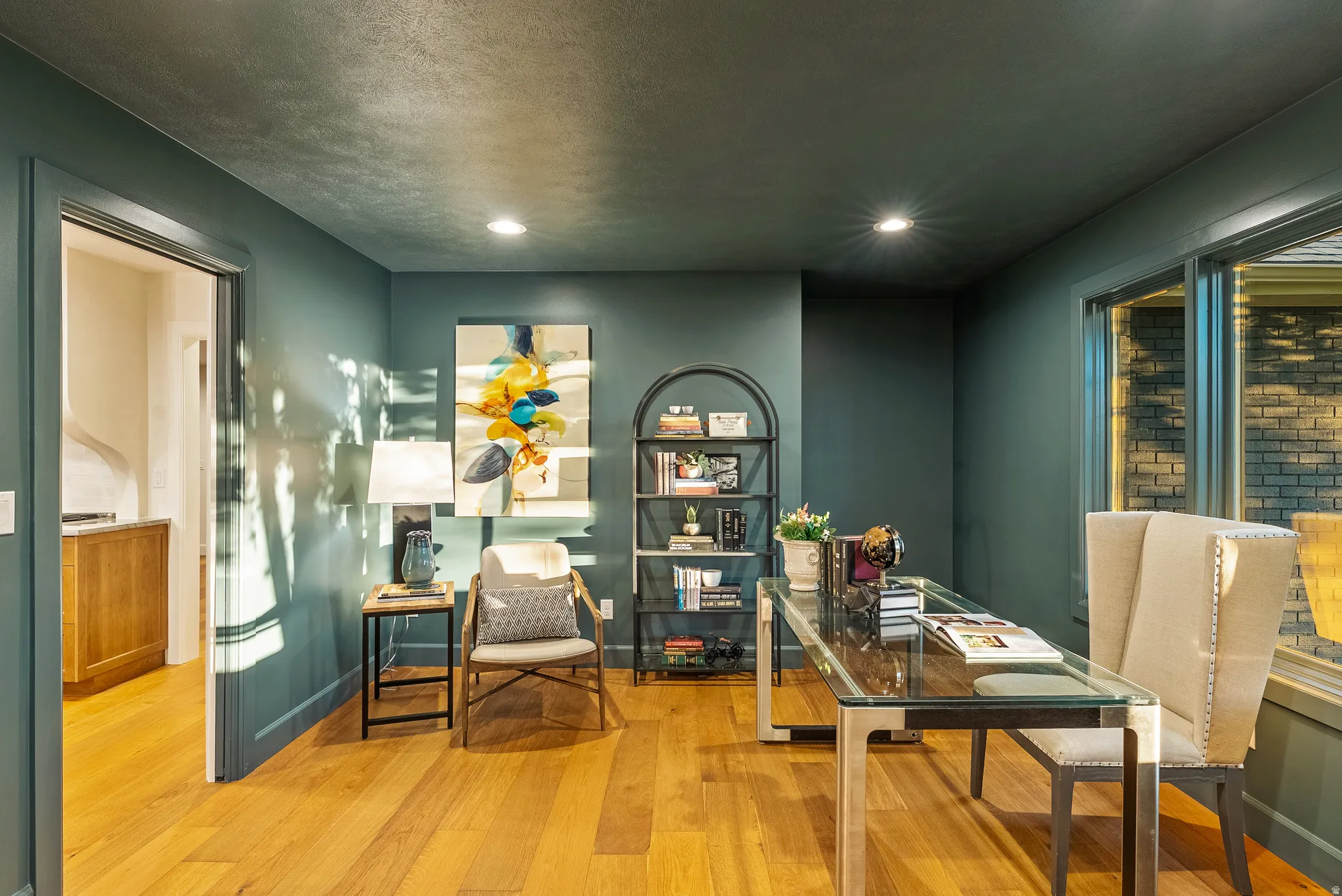 Room featuring dark green painted walls, recessed lighting, wood-finish flooring, and a large window overlooking a brick exterior