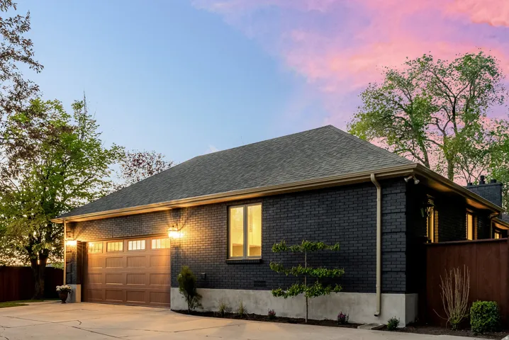 Black brick exterior with a dark shingle roof and contrasting beige gutters