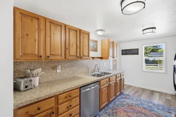 Kitchen featuring wood-finish cabinetry, speckled countertops, and a stainless steel dishwasher