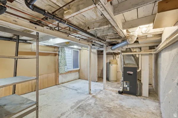 Unfinished basement featuring exposed joists, concrete flooring, and visible utility lines