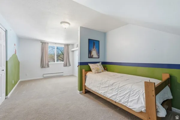 Carpeted room with a ceiling light fixture, a window, and a built-in baseboard heater