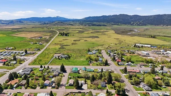 Aerial perspective showcasing a residential neighborhood with a backdrop of expansive green fields and distant mountains