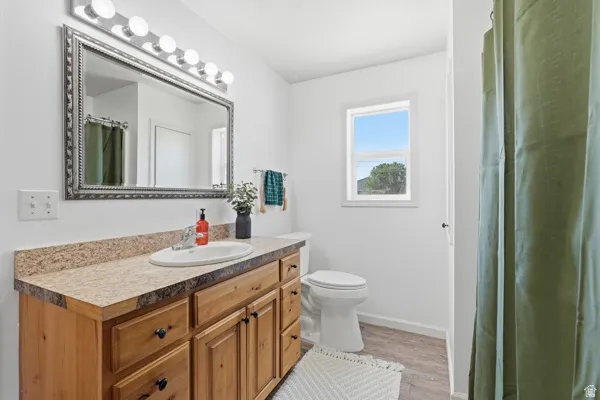 Bathroom featuring a wood-finish vanity with ample storage, a light-toned countertop, and an oval undermount sink