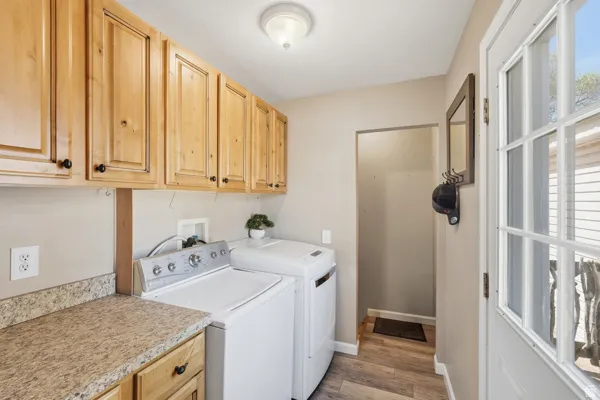 Functional laundry area featuring extensive wood cabinetry, mottled countertop space, and wood-finish flooring