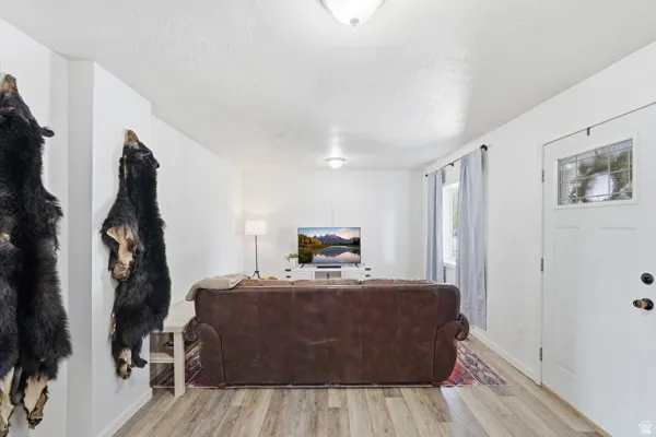 Open living area featuring wood-finish flooring, white walls, and a recessed window with light-colored drapes