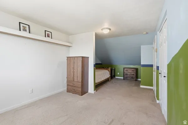 Carpeted room featuring a built-in display shelf, a sloped ceiling portion, a flush-mount ceiling light, and two white bi-fold closet doors