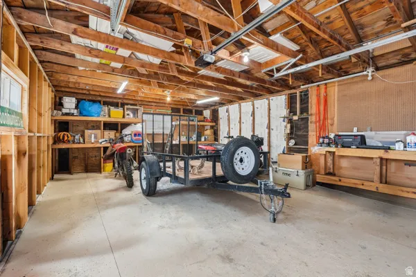 Utility space featuring exposed wood framing, concrete flooring, and built-in shelving