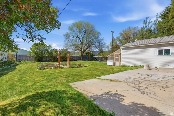 Expansive backyard featuring a manicured lawn, established garden beds, and a functional greenhouse