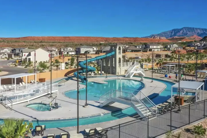 Resort-style aquatic amenity featuring a large swimming pool, a separate spa, a lazy river, and a water slide tower
