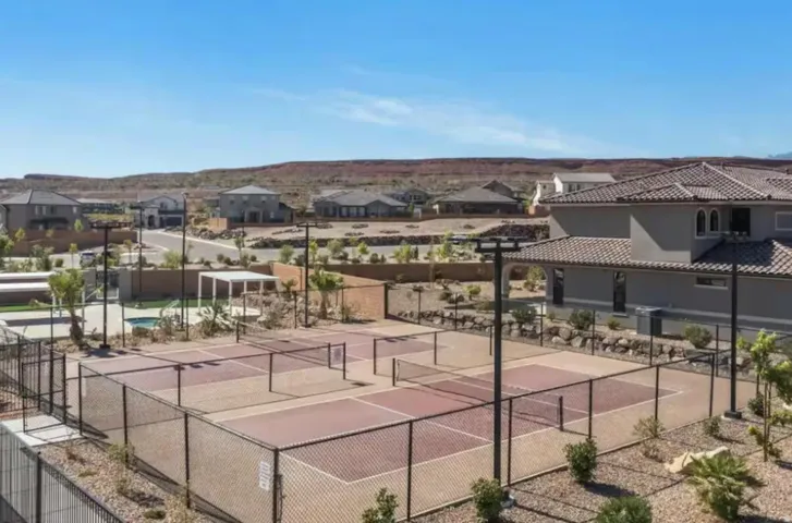 Community recreation area featuring multiple fenced pickleball courts, a swimming pool, and a shaded pergola