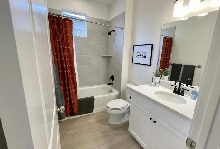 Full bathroom featuring a white vanity with a solid surface countertop, an undermount sink, and matte black fixtures