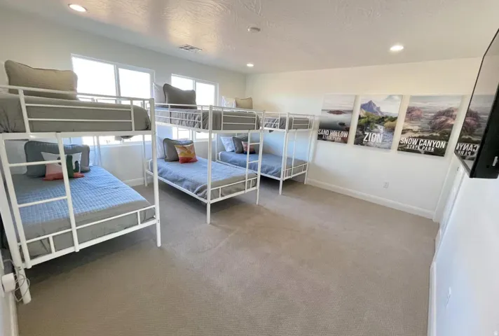 Spacious room featuring multiple windows with natural light, light-colored carpeting, recessed ceiling lighting, and wall-mounted decor
