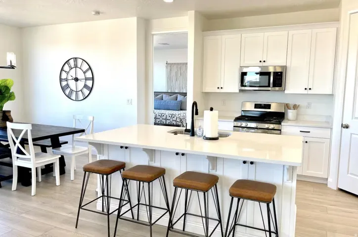 Kitchen featuring white shaker cabinetry, stainless steel appliances, and light-tone wood-finish flooring