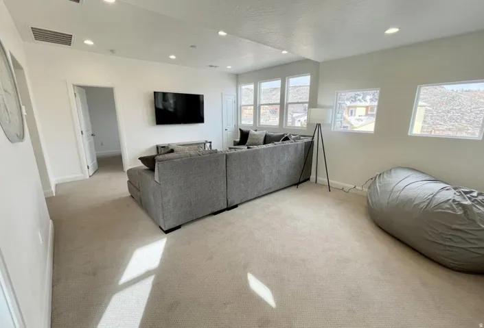 Spacious bonus room featuring light neutral carpeting, recessed ceiling lighting, and multiple windows providing natural illumination
