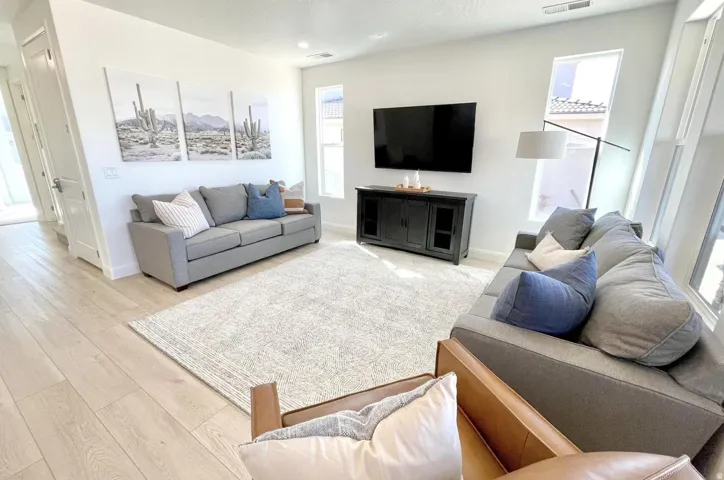 Bright living area featuring light wood-finish flooring, recessed lighting, multiple windows, a ceiling vent, and white baseboards