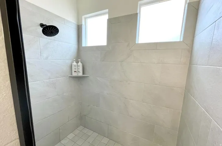 Walk-in shower with light-toned rectangular tile walls and square tile flooring