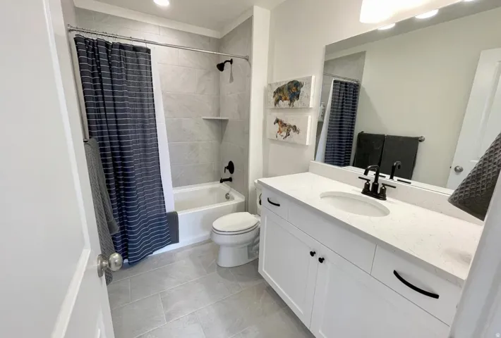 Bathroom featuring a white vanity with a light-toned countertop, undermount sink, and matte black fixtures