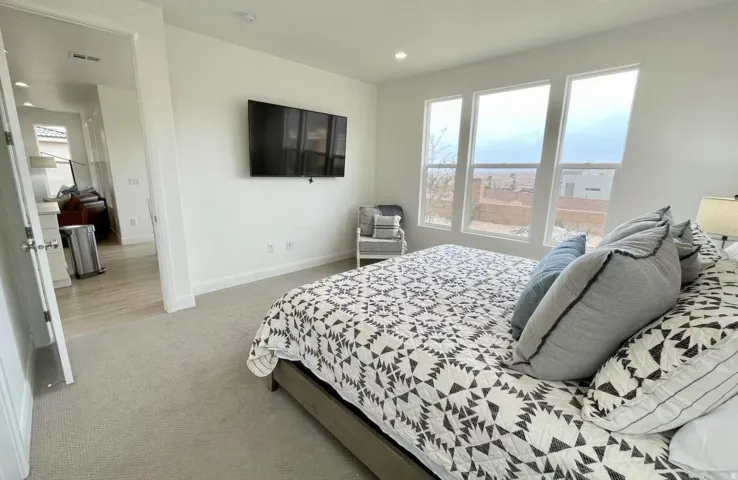 Carpeted room with a wall-mounted television and three large windows