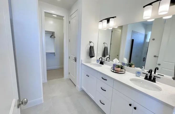 Dual vanity with white cabinetry and integrated sinks, complemented by a large mirror and black fixtures