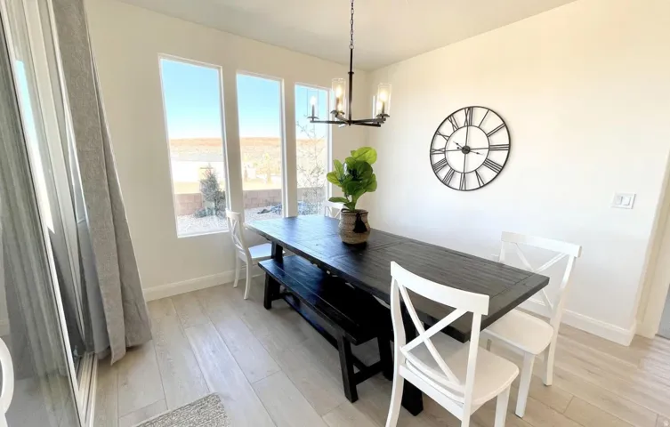 Bright dining area featuring a modern chandelier, light wood-finish flooring, a large sliding glass door, and multiple vertical windows