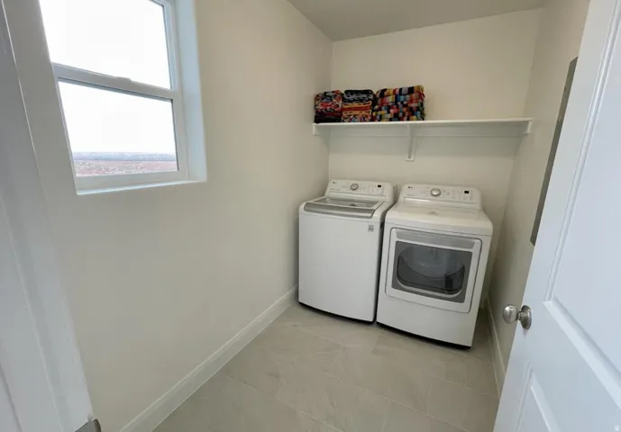 Dedicated laundry area featuring a window, built-in shelving, and light-toned floor tiling