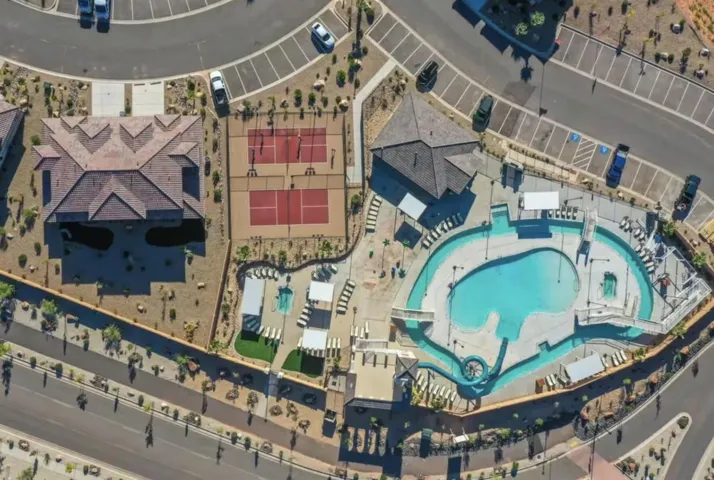 Expansive community amenity area featuring a large resort-style pool with a lazy river, two tennis courts, and multiple surrounding structures with covered patio areas