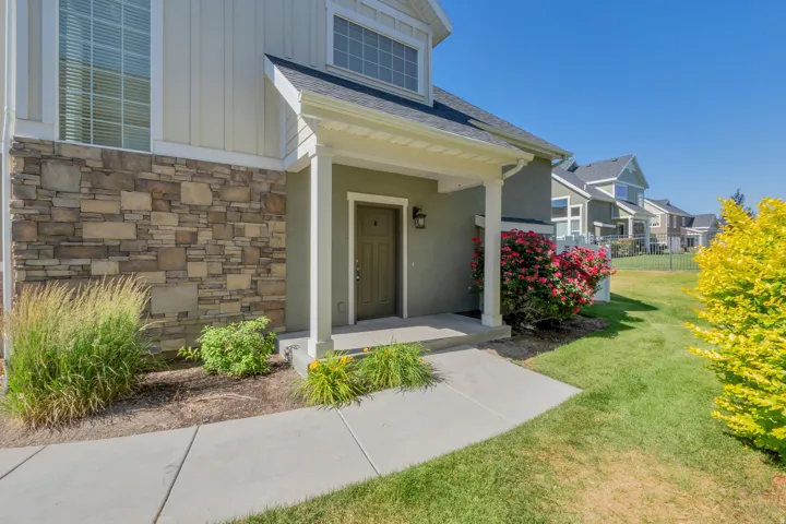 Entryway featuring a covered porch, stone facade accents, and board and batten siding