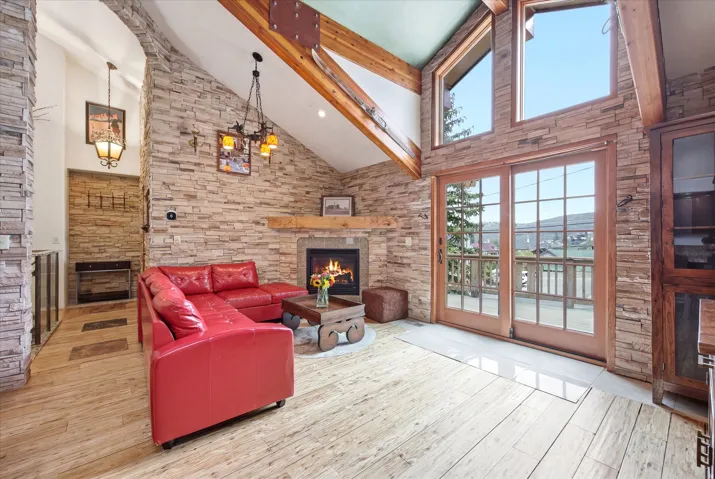 Vaulted ceiling living area featuring a stone accent wall and fireplace with wood mantel