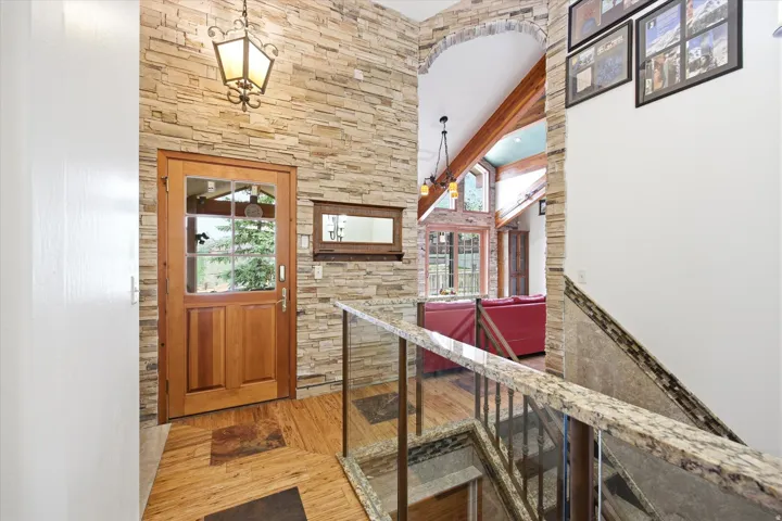 Stone accent wall with a glass-paneled wooden entry door, featuring a decorative overhead lantern