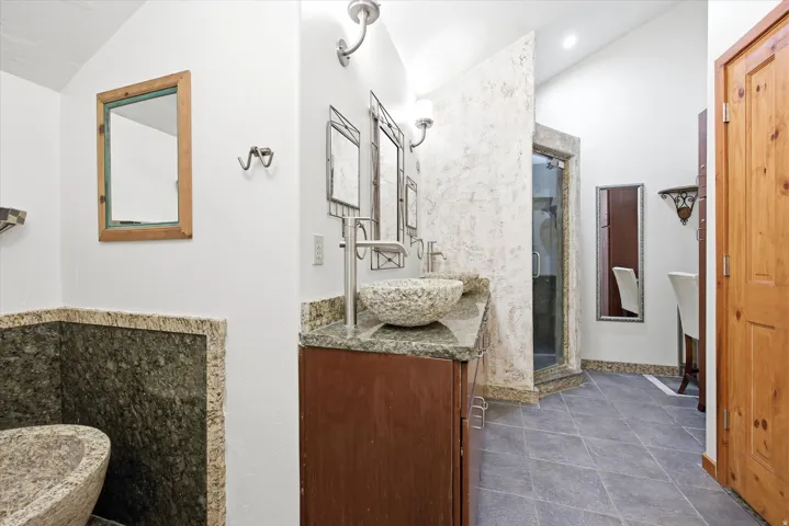 Tiled flooring throughout with a stone-surround shower stall featuring a glass door