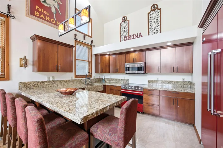 Kitchen featuring granite countertops, wood cabinetry, Viking refrigerator, range and microwave.