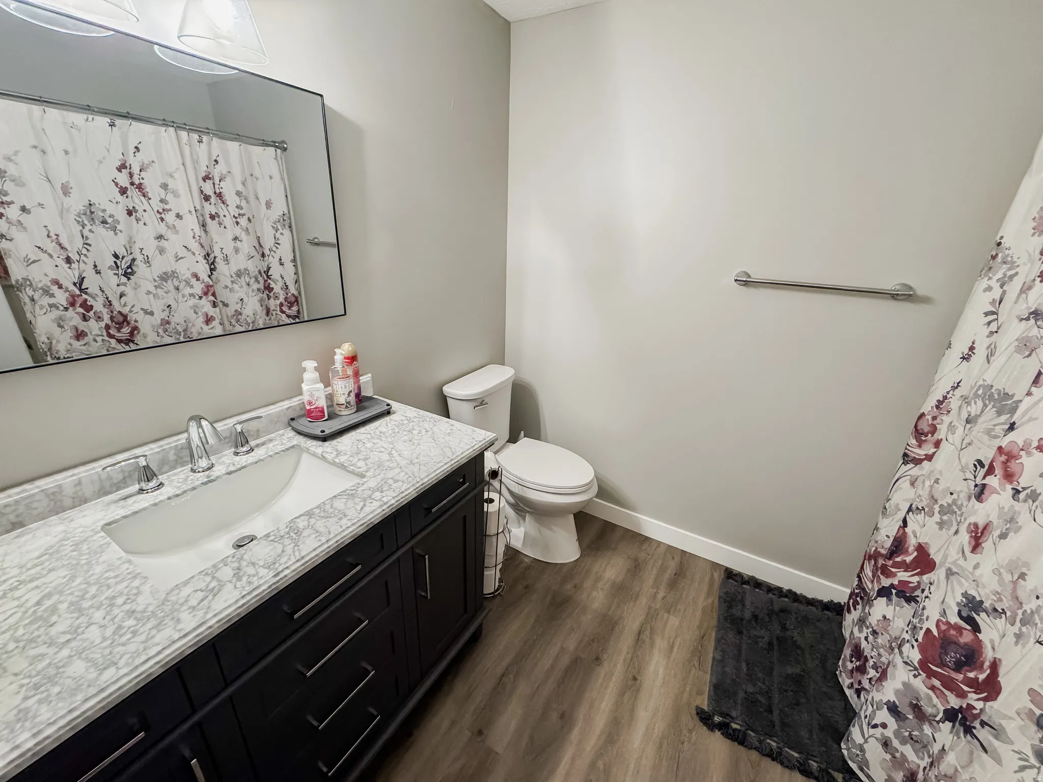 Bathroom featuring a dark wood vanity with a white marbled-finish countertop, undermount sink, and chrome fixtures