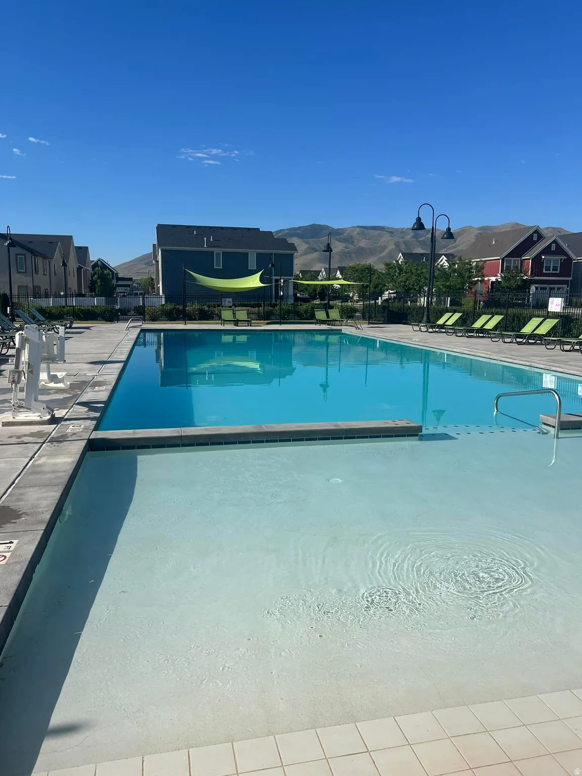 Community swimming pool featuring a shallow entry area, a deeper swimming section, and surrounding patio space with lounge chairs