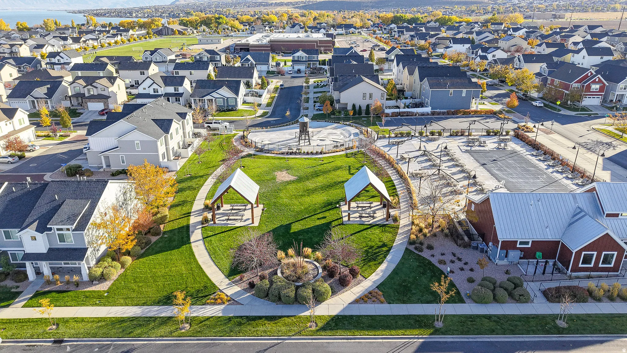 Expansive community park featuring manicured lawns, paved walking paths, and two covered picnic shelters