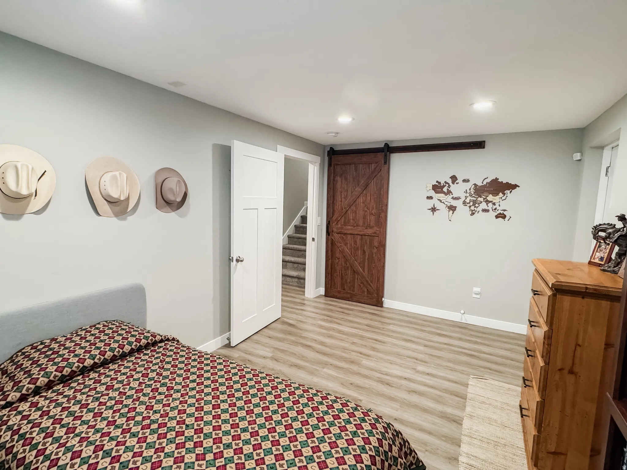 Spacious room featuring light wood-finish flooring, recessed lighting, and a modern barn door