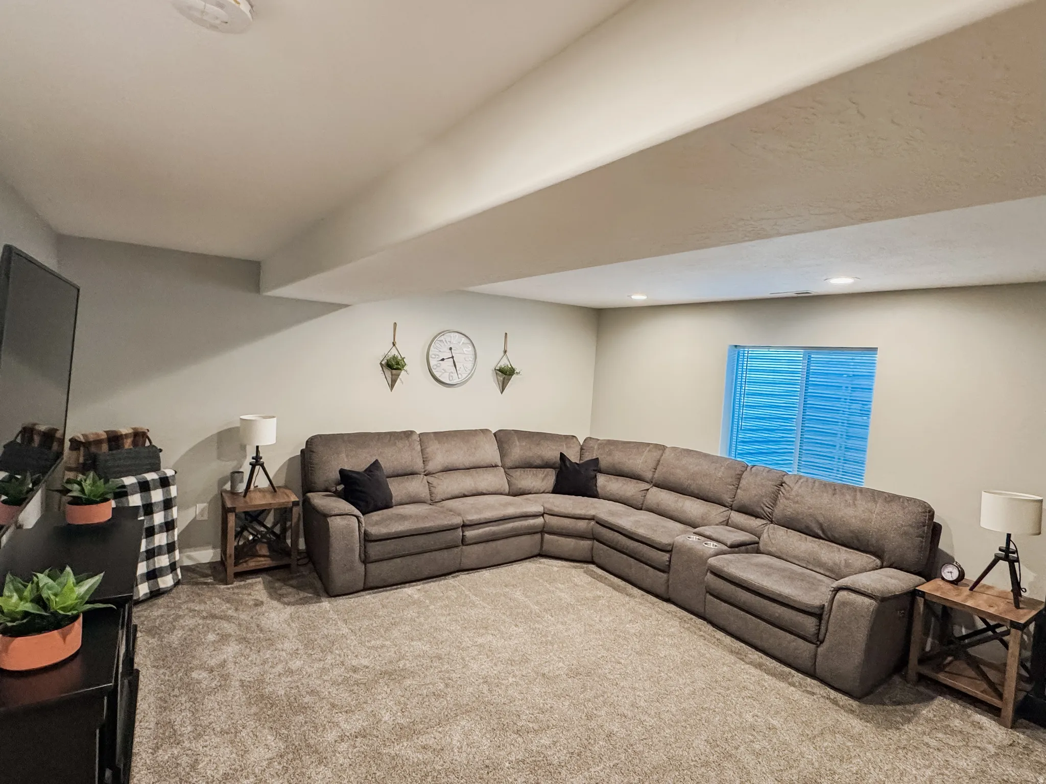 Recessed lighting illuminates the room, featuring light gray walls and plush carpet flooring