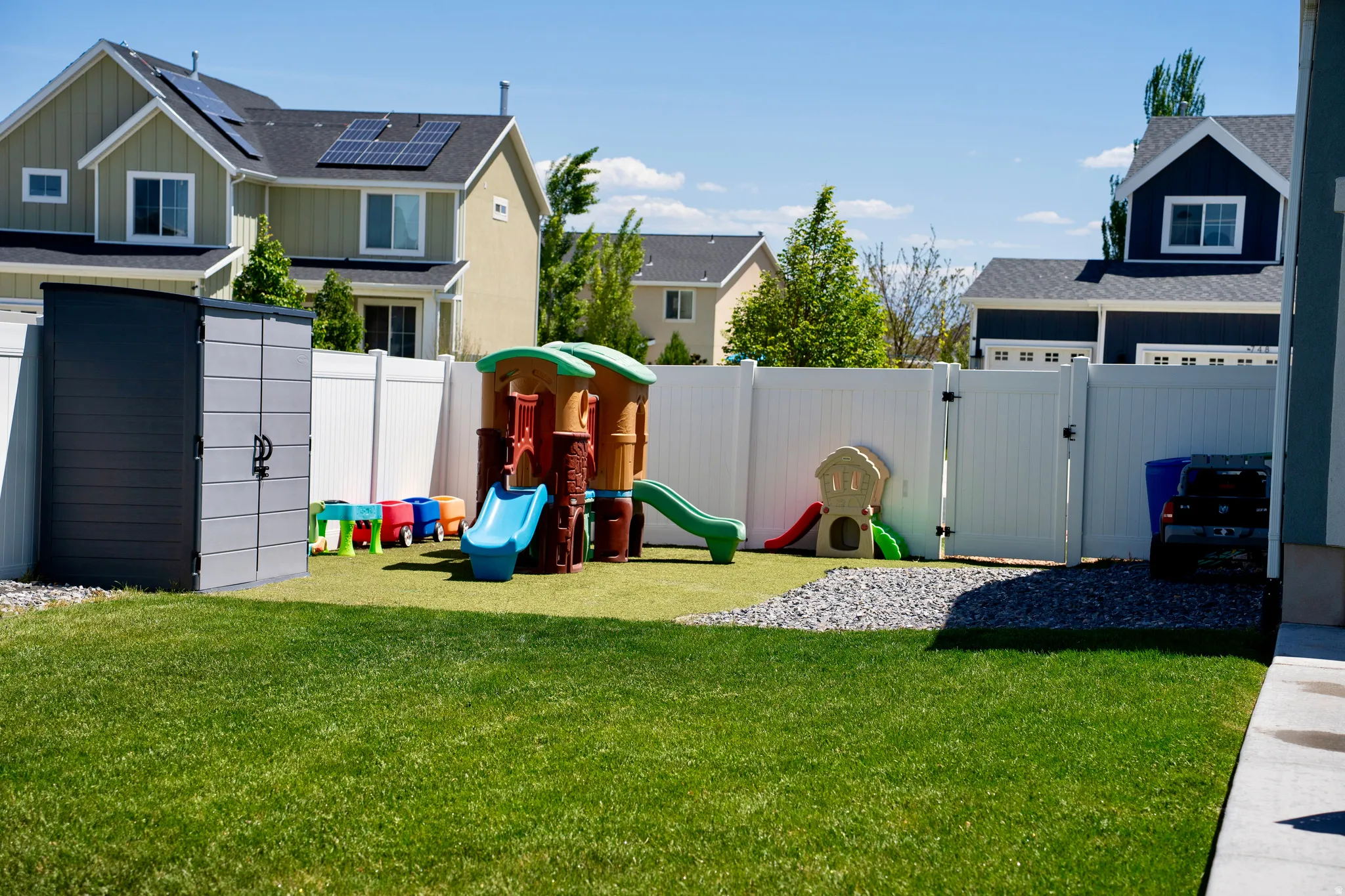 Expansive green lawn with a white vinyl fence and a dedicated artificial turf area