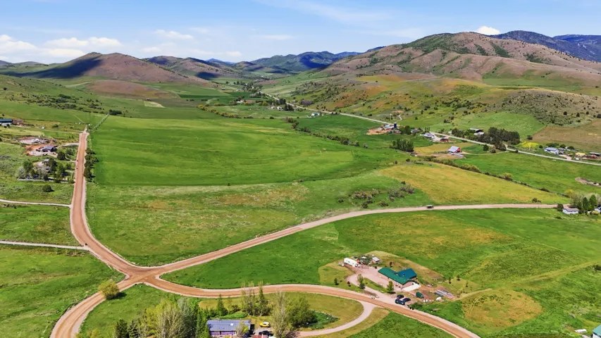 Expansive green fields with rolling hills and distant mountains