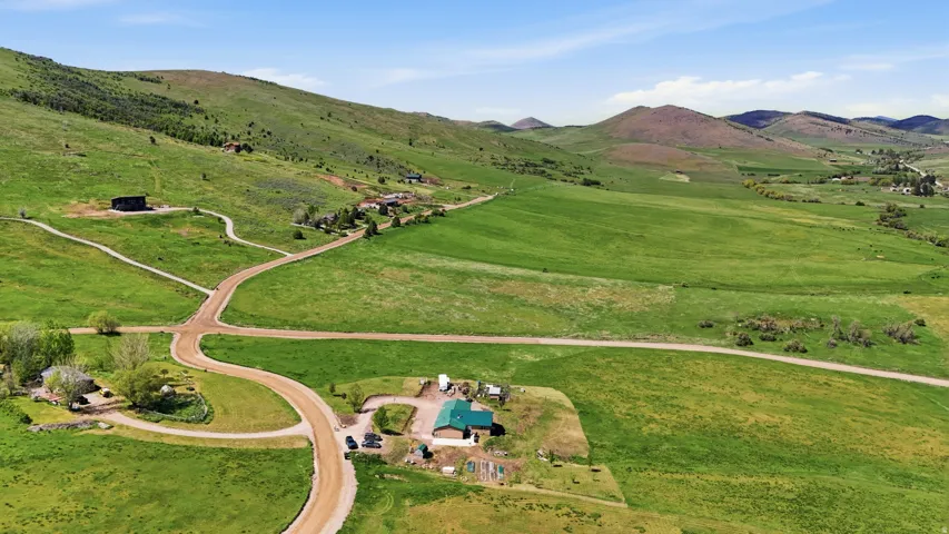 Expansive green landscape featuring rolling hills and multiple structures