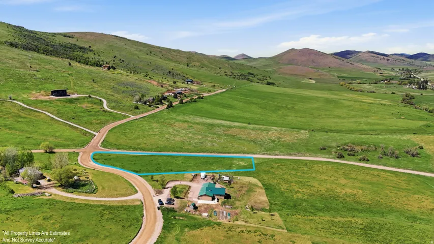 Expansive land parcel featuring a designated blue outline, surrounded by verdant hillsides and open fields-boundary lines are for visual only