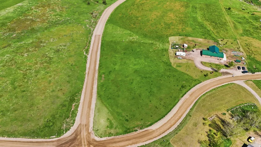 Aerial depiction of a property featuring a central building with a green roof, surrounded by extensive green land
